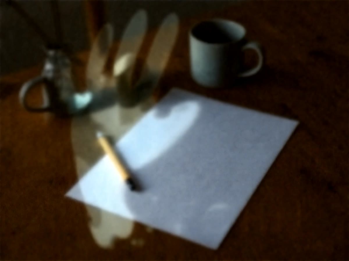 Paper, a pencil, and a mug on a wooden table